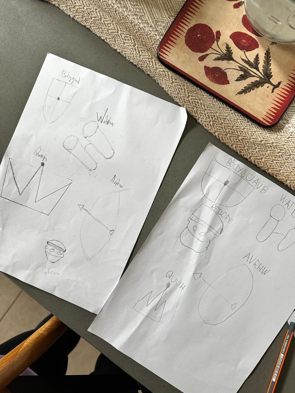 Two sheets of paper with technical drawings on a table.